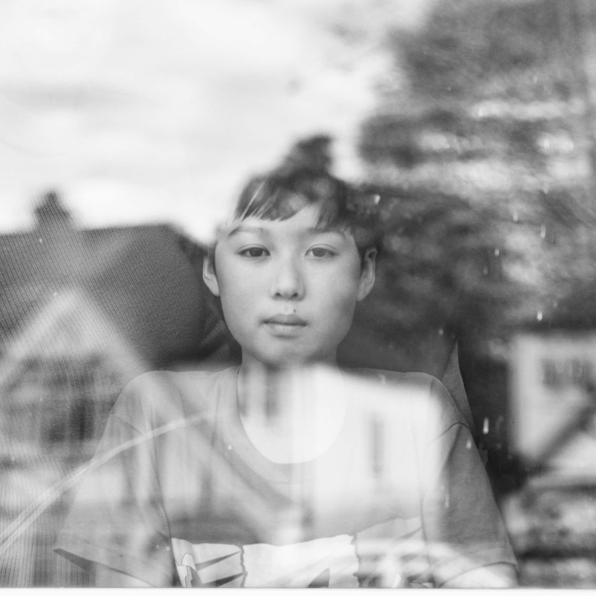 Asian boy behind window with reflections from outside during Corona Virus