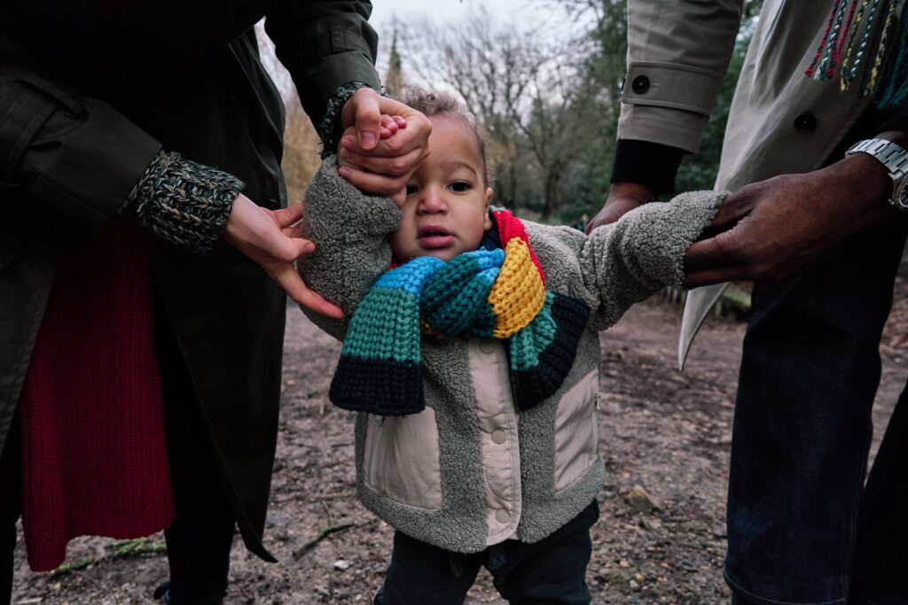 Boy learning to walk being captured using a big mirrorless camera 