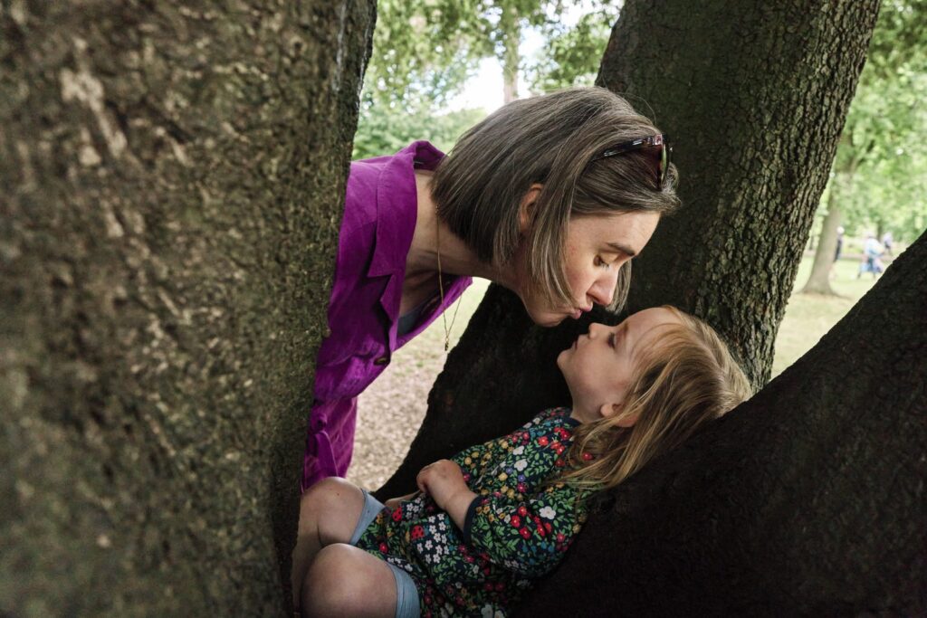 Mother kissing her young daughter during a real-life family photo session in London. 