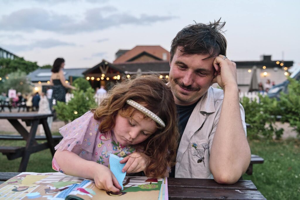 Inclusive family photography showing a child focused on sticking stickers during an outdoor party  in London